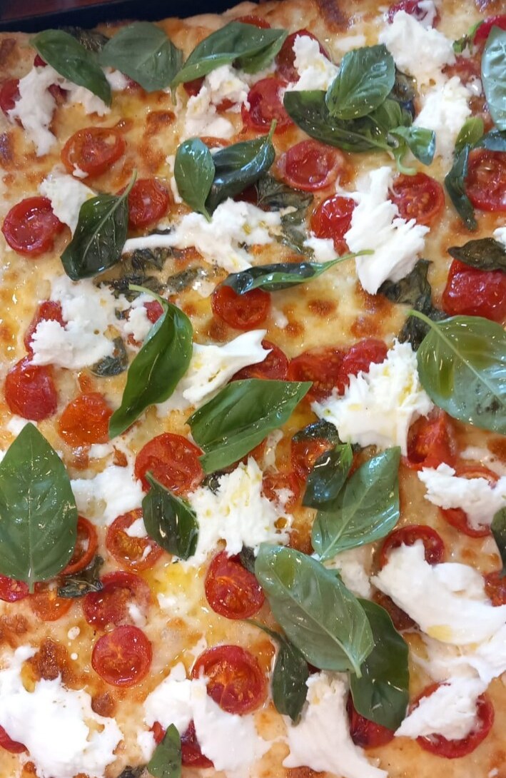 Pizza in teglia con pomodorini, basilico e mozzarella